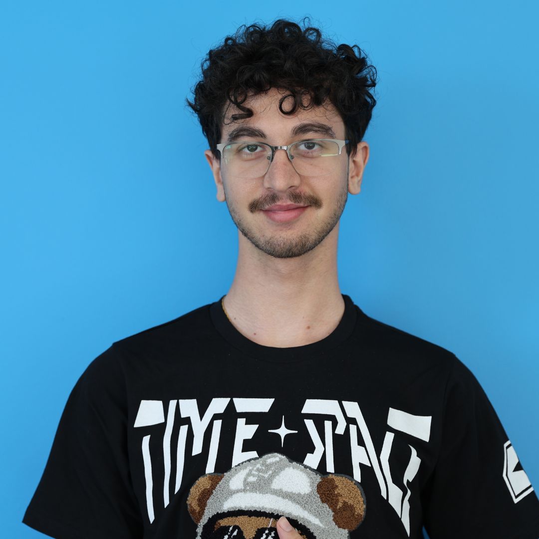 Young man smiling in black shirt in front of blue background