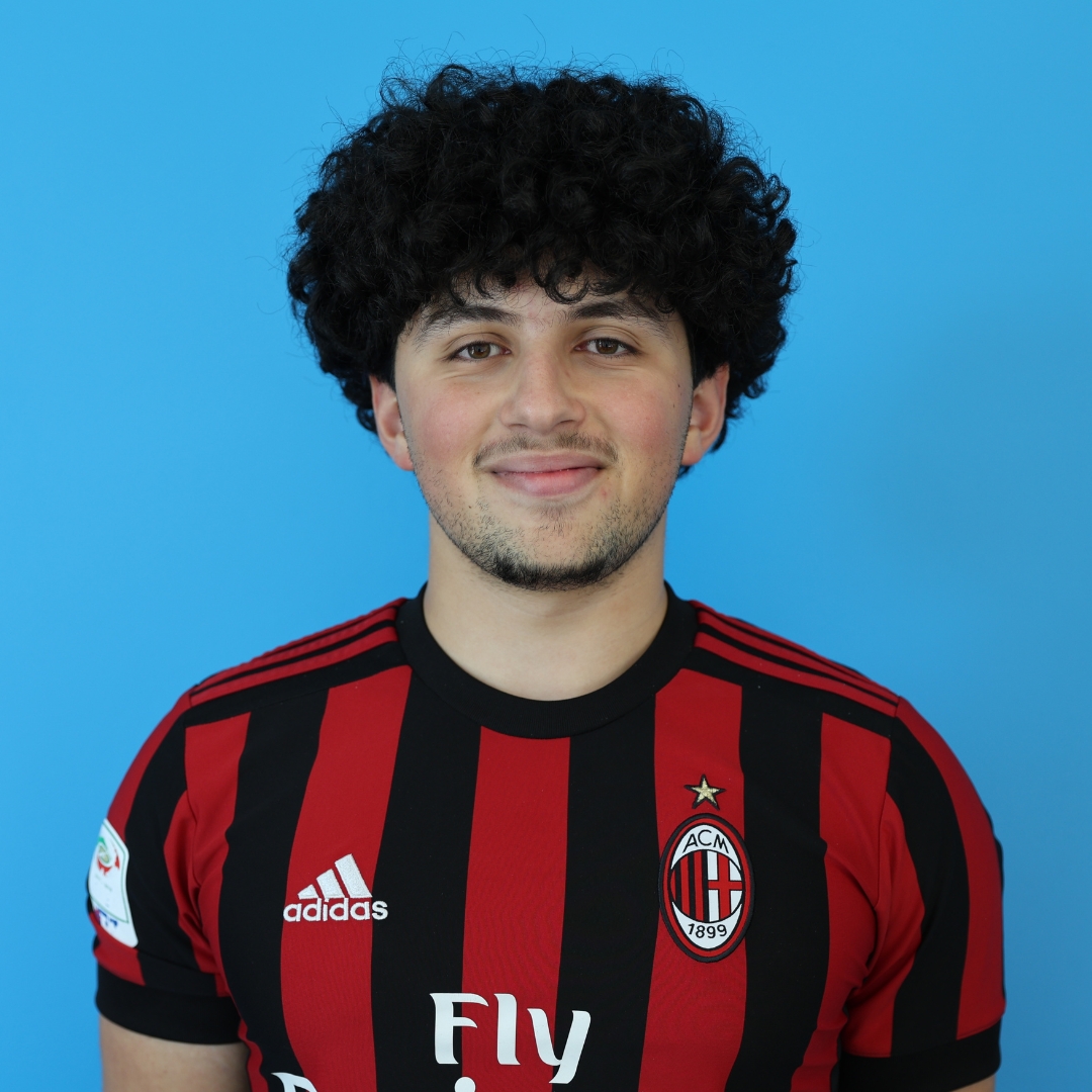 Photo of a young man wearing a football jersey, smiling against a blue background.