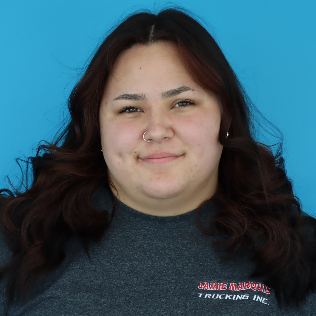 A smiling young woman with curly hair wearing a gray t-shirt featuring the Jamie Marquis Trucking Inc. logo.