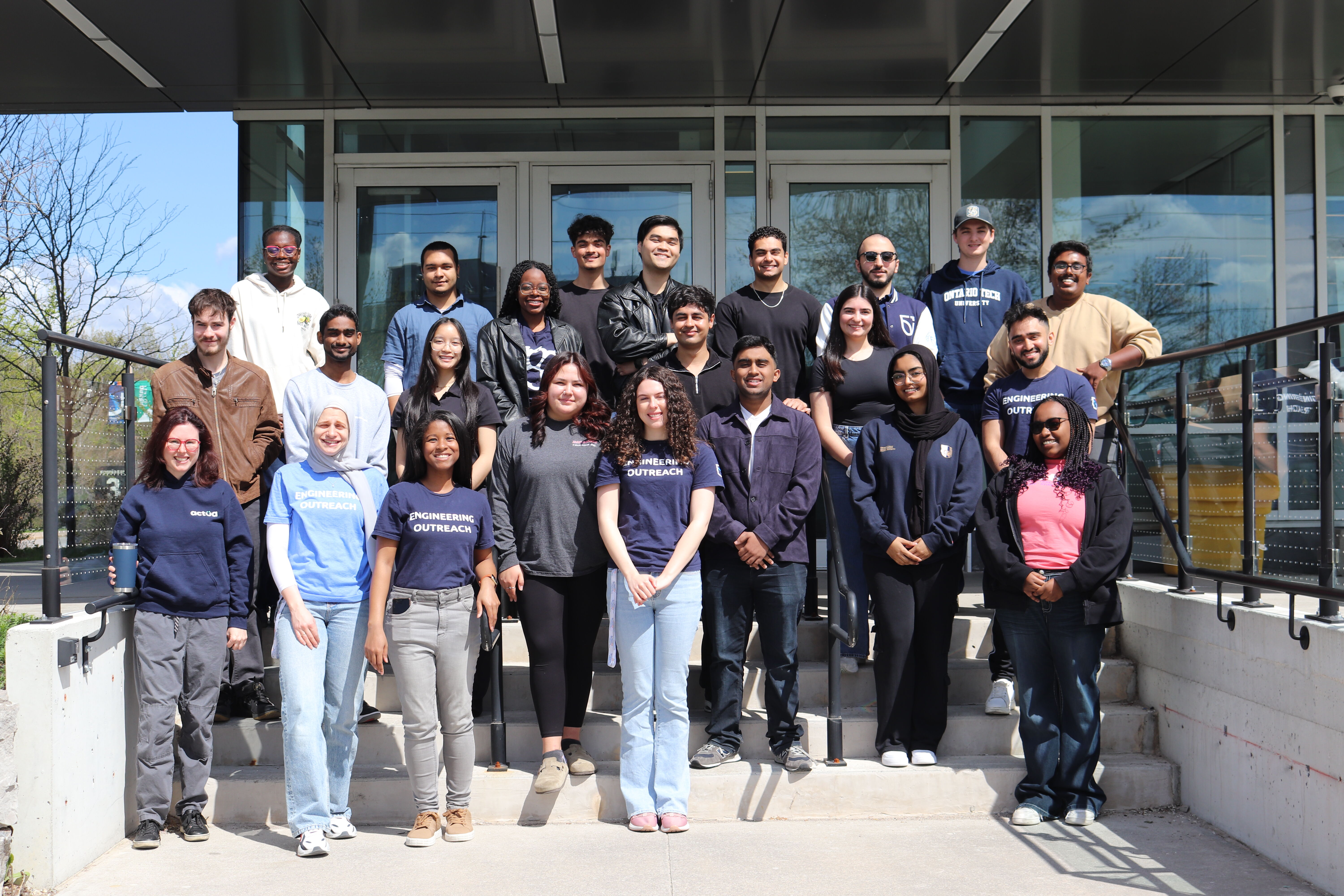 Group photo of diverse students and staff posing on the steps of a building.