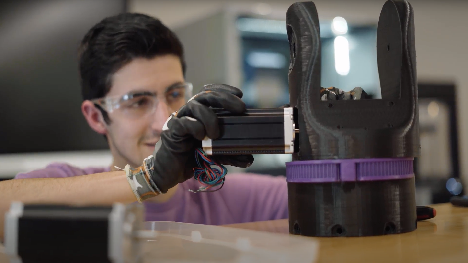 photo of a 3d printed part, a man is blurry in the background working on it