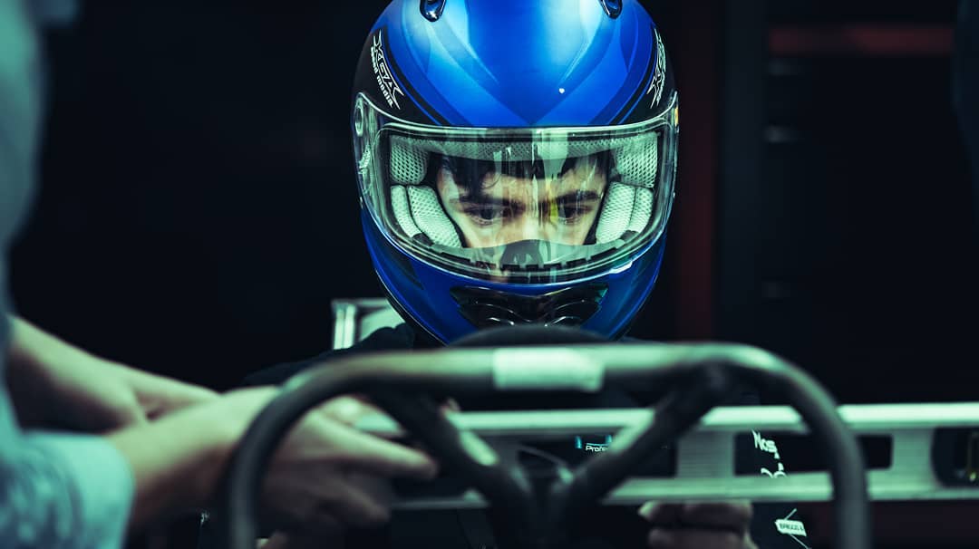 Student sits in the Ontario Tech Race Team car with a helmet on.