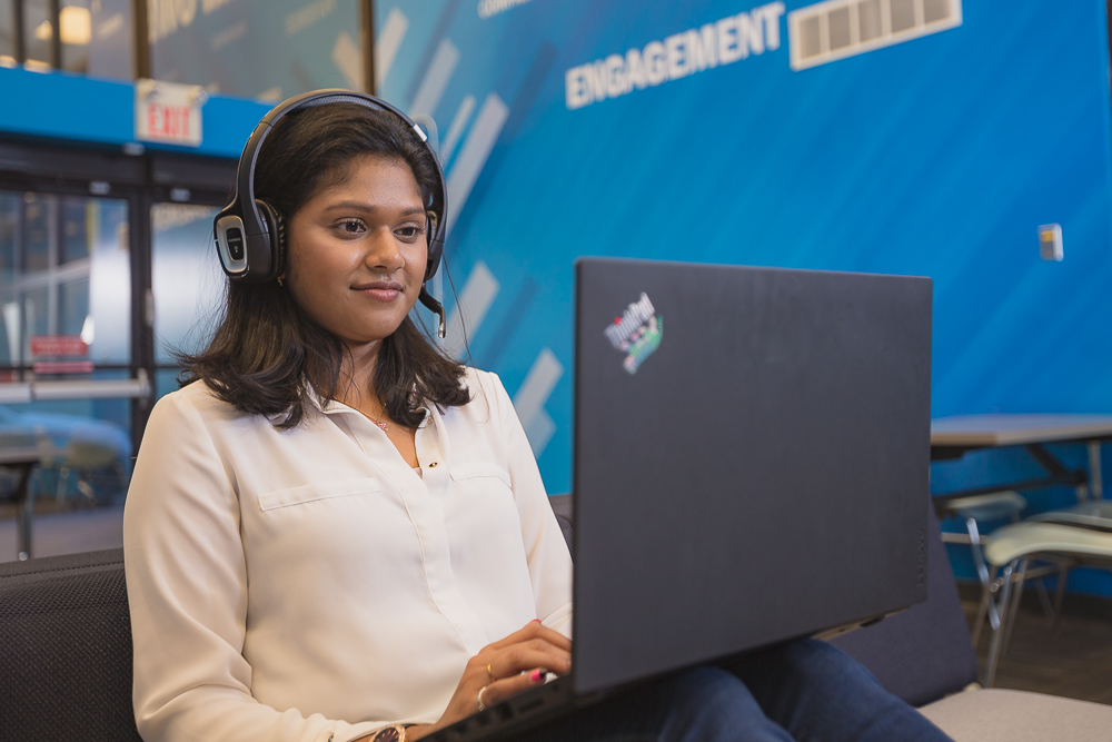 A student wearing headphones sits in front of an open laptop.