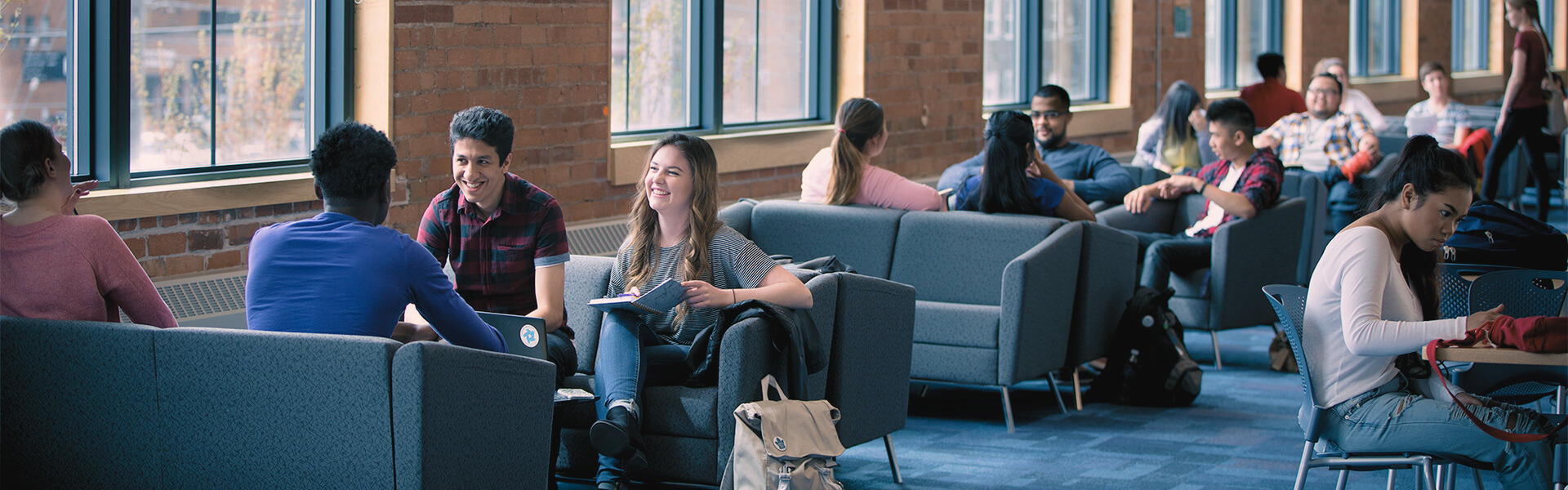 A group of students sitting on couches across from one another in the second floor atrium at Charles Hall. 