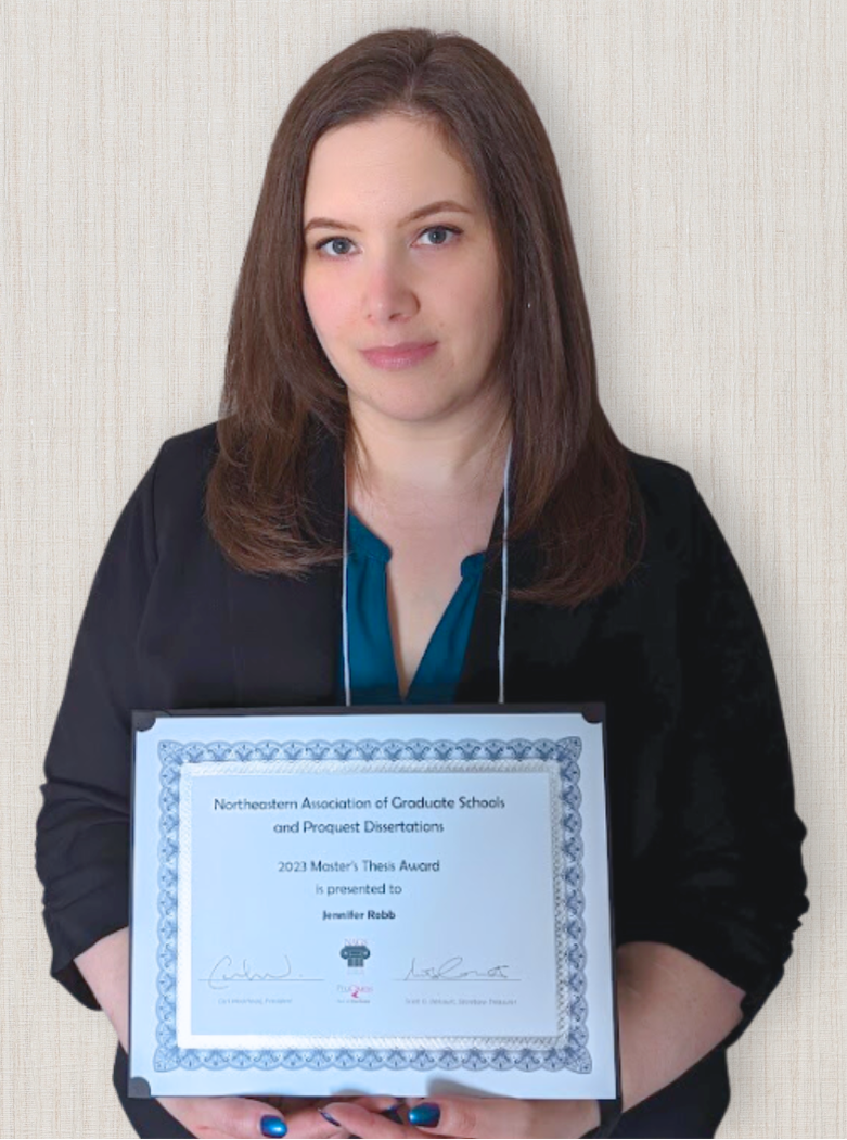 Jennifer Robb, wearing a teal shirt and black cardigan, holding her Master's Thesis Award certificate from NAGS and ProQuest Dissertations.