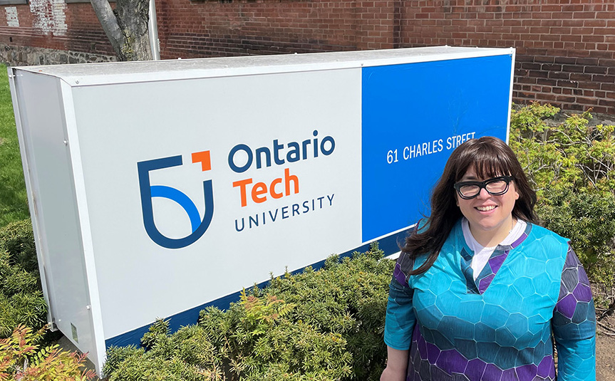 Dr. Robyn Ruttenberg-Rozen stands in front of the address sign at Ontario Tech University's Charles Hall.