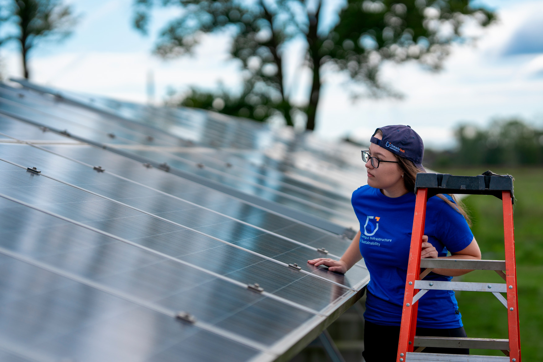 A student works on a solar panel in a field.