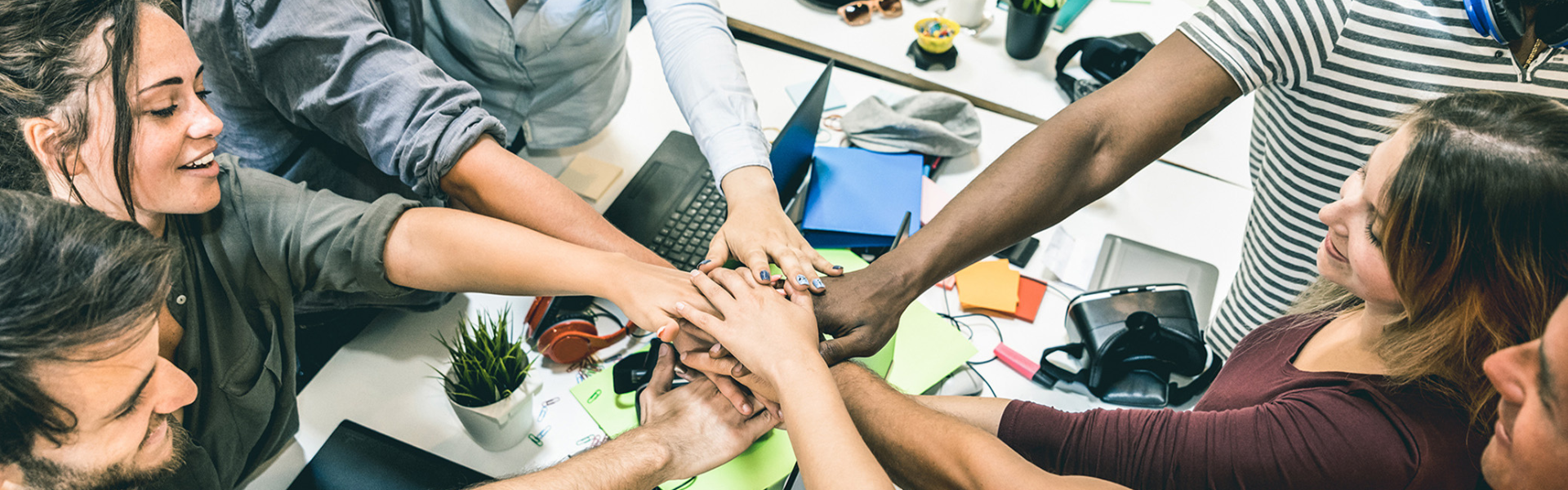 Young professionals showing unity by placing hand in a cirlce. 