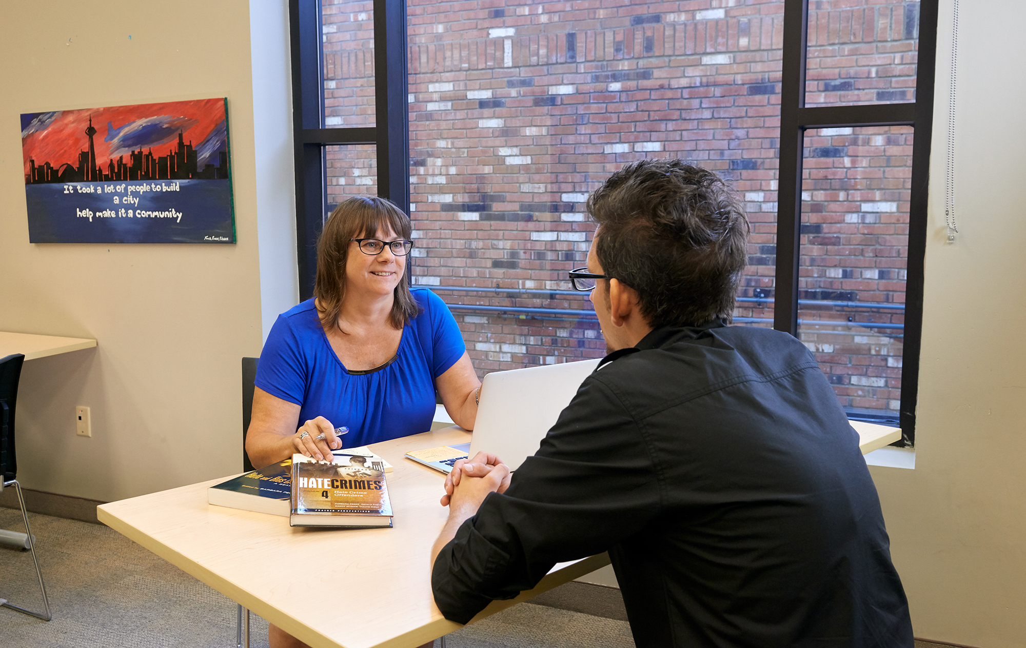 Dr. Barbara Perry sits at a table having a conversation with a man.