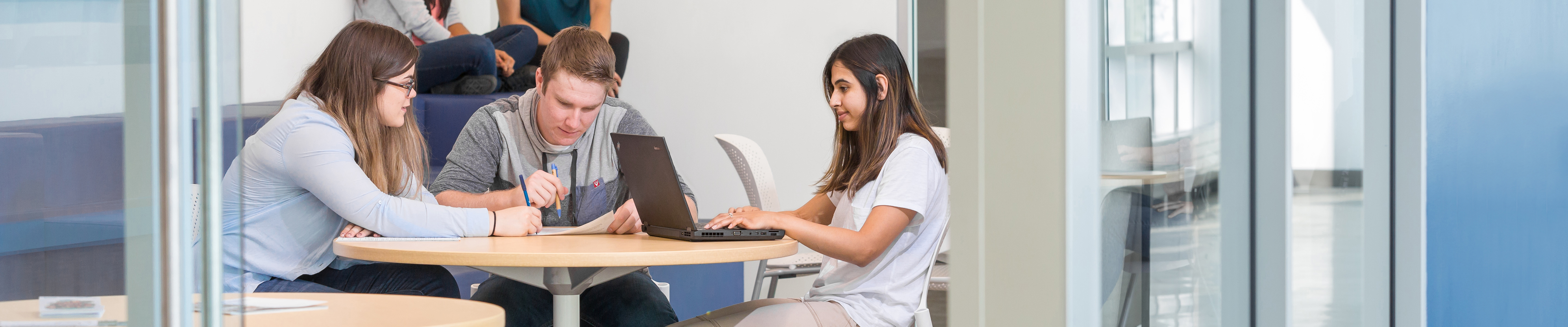 An image of 3 students sitting together with a laptop.