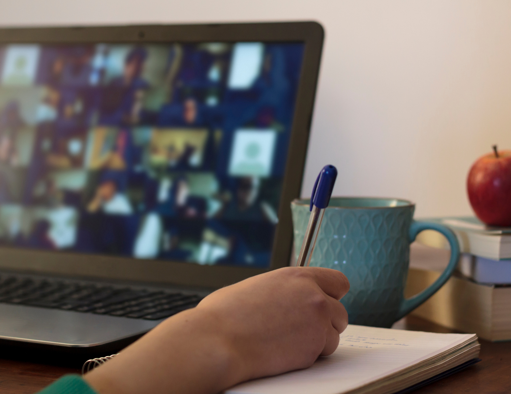 An image of a person on a video conference call taking notes.