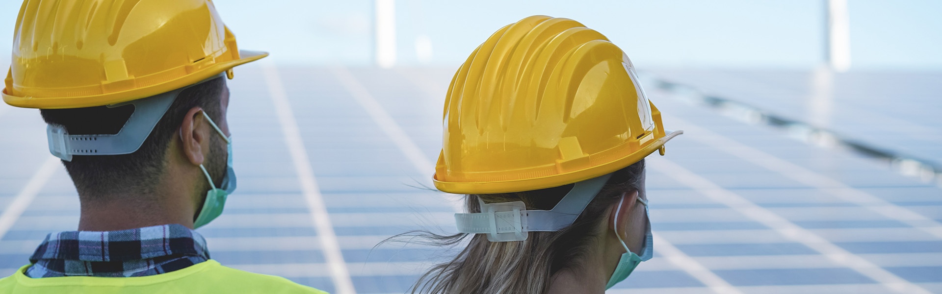 Two people surveying a solar panel array